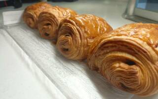 Les croissants et les pains au chocolat sont deux piliers de la tradition culinaire française, particulièrement appréciés lors des petits déjeuners ou des brunchs dominicaux. Leur texture feuilletée, leur goût riche et leur aspect doré les rendent irrésistibles. Cependant, leur composition nutritionnelle soulève des questions quant à leur impact sur la santé. Riches en calories, en graisses et en sucres, leur consommation mérite une attention particulière. Un combat serré sur le plan calorique D'un côté, nous avons le croissant, symbole de la pâtisserie française, contenant entre 230 et 270 calories. De l'autre, le pain au chocolat, garni de barres de chocolat fondant, apporte entre 250 et 300 calories. Le contenu lipidique de ces deux options est similaire, avoisinant les 25 grammes, bien que le pain au chocolat prenne une légère avance en raison de son ajout de chocolat. Les enjeux nutritionnels des viennoiseries Ces délices matinaux sont souvent catégorisés comme des aliments "plaisir", offrant une satisfaction gustative immédiate sans contribuer de manière significative à l'équilibre nutritionnel. La présence de graisses saturées et de sucres rapides, qui dominent leur composition, nécessite une consommation modérée. Ces composants peuvent entraîner des pics glycémiques suivis de baisses rapides, affectant l'énergie et augmentant le désir de sucre. Conseils pour une consommation responsable Pour atténuer les effets moins désirables des viennoiseries, il est recommandé de les accompagner d'aliments riches en protéines et en fibres, tels que des crudités ou des œufs. Cette association aide à stabiliser l'absorption des graisses et des sucres. De plus, consommer ces gourmandises avant 16 heures pourrait optimiser la digestion des graisses saturées. La modération : clé d'un petit déjeuner équilibré Bien que le choix entre un croissant et un pain au chocolat puisse paraître mineur, il révèle une considération importante pour notre bien-être. Ces viennoiseries, tout en étant des sources de plaisir, doivent être intégrées dans notre alimentation de façon judicieuse et informée. Elles incarnent le plaisir gustatif mais doivent être consommées avec parcimonie pour maintenir un équilibre nutritionnel.