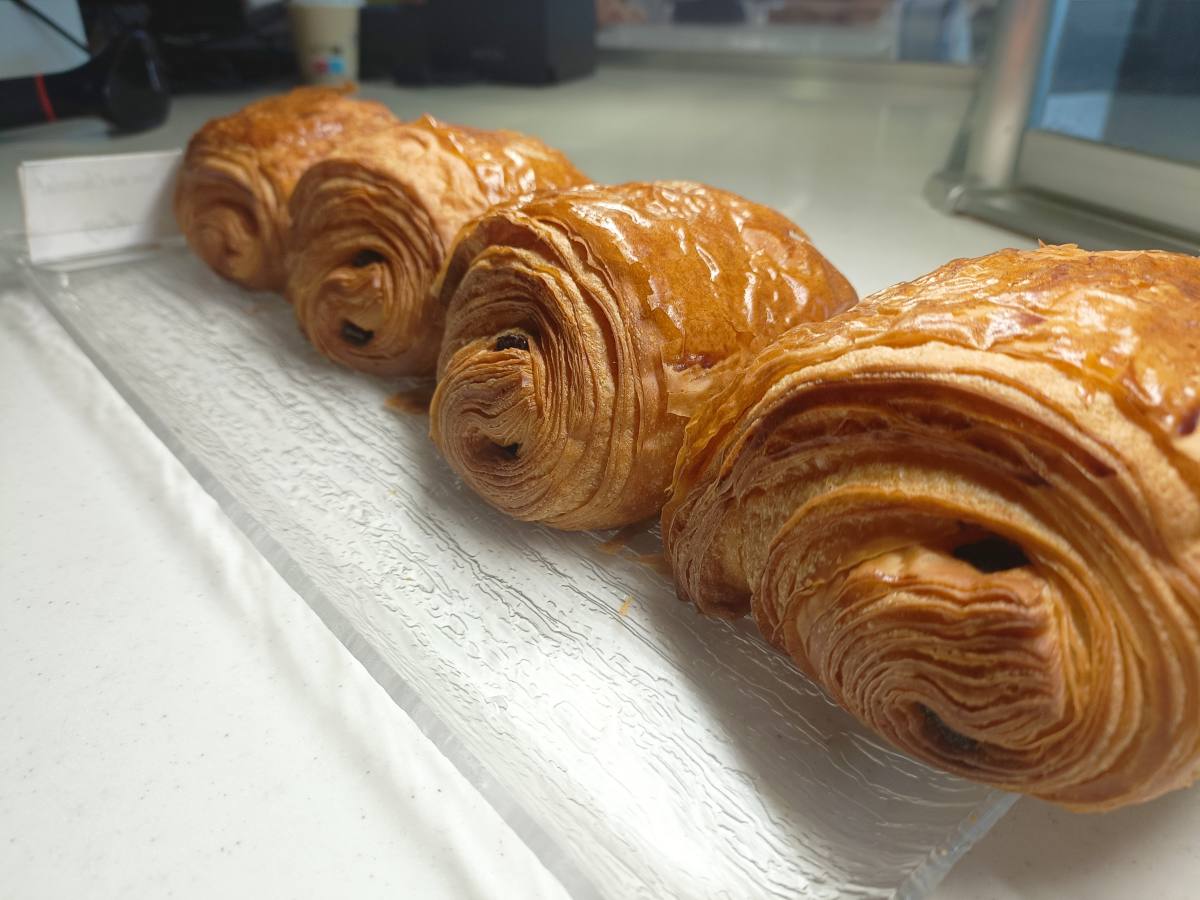 Les croissants et les pains au chocolat sont deux piliers de la tradition culinaire française, particulièrement appréciés lors des petits déjeuners ou des brunchs dominicaux. Leur texture feuilletée, leur goût riche et leur aspect doré les rendent irrésistibles. Cependant, leur composition nutritionnelle soulève des questions quant à leur impact sur la santé. Riches en calories, en graisses et en sucres, leur consommation mérite une attention particulière. Un combat serré sur le plan calorique D'un côté, nous avons le croissant, symbole de la pâtisserie française, contenant entre 230 et 270 calories. De l'autre, le pain au chocolat, garni de barres de chocolat fondant, apporte entre 250 et 300 calories. Le contenu lipidique de ces deux options est similaire, avoisinant les 25 grammes, bien que le pain au chocolat prenne une légère avance en raison de son ajout de chocolat. Les enjeux nutritionnels des viennoiseries Ces délices matinaux sont souvent catégorisés comme des aliments "plaisir", offrant une satisfaction gustative immédiate sans contribuer de manière significative à l'équilibre nutritionnel. La présence de graisses saturées et de sucres rapides, qui dominent leur composition, nécessite une consommation modérée. Ces composants peuvent entraîner des pics glycémiques suivis de baisses rapides, affectant l'énergie et augmentant le désir de sucre. Conseils pour une consommation responsable Pour atténuer les effets moins désirables des viennoiseries, il est recommandé de les accompagner d'aliments riches en protéines et en fibres, tels que des crudités ou des œufs. Cette association aide à stabiliser l'absorption des graisses et des sucres. De plus, consommer ces gourmandises avant 16 heures pourrait optimiser la digestion des graisses saturées. La modération : clé d'un petit déjeuner équilibré Bien que le choix entre un croissant et un pain au chocolat puisse paraître mineur, il révèle une considération importante pour notre bien-être. Ces viennoiseries, tout en étant des sources de plaisir, doivent être intégrées dans notre alimentation de façon judicieuse et informée. Elles incarnent le plaisir gustatif mais doivent être consommées avec parcimonie pour maintenir un équilibre nutritionnel.